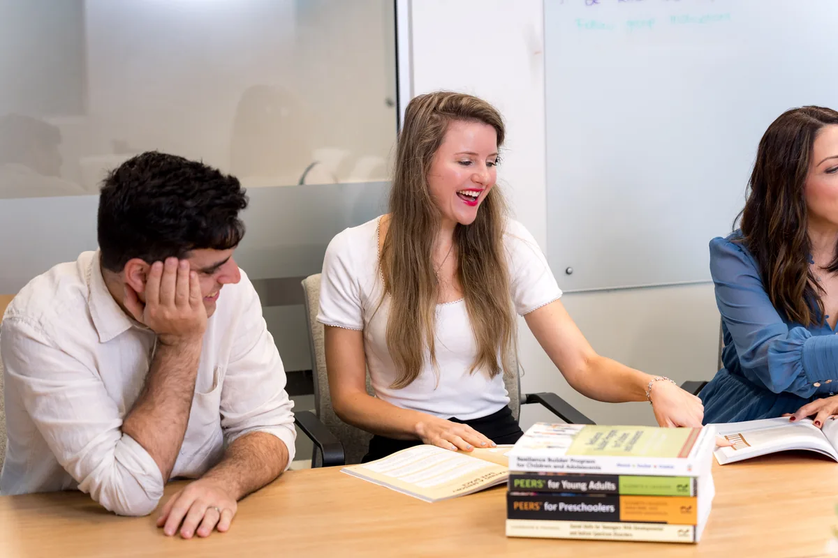 Two clinicians planning a program at a table covered with workbooks and resources