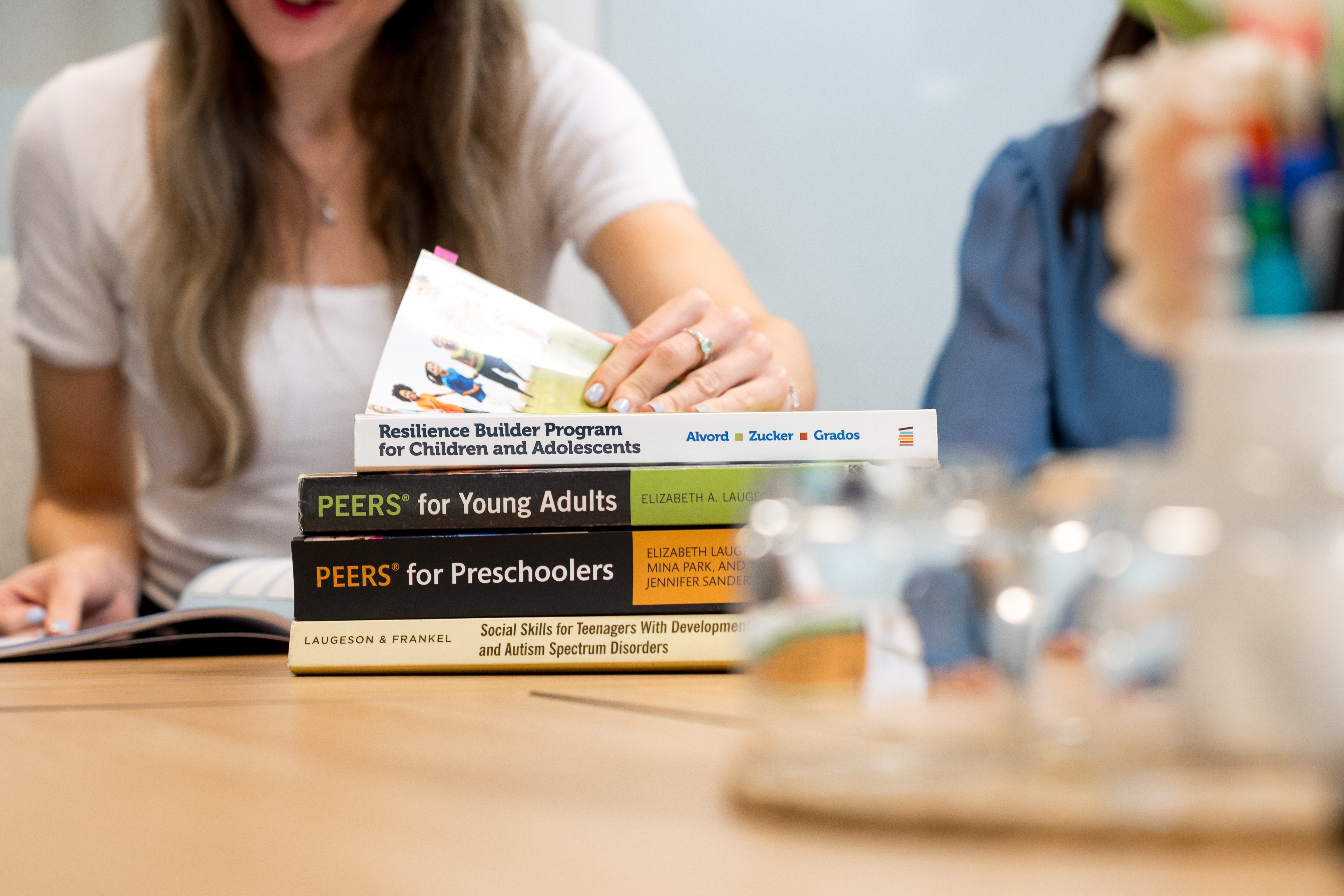 A stack of the clinic's PEERS® and social skills program manuals on the table