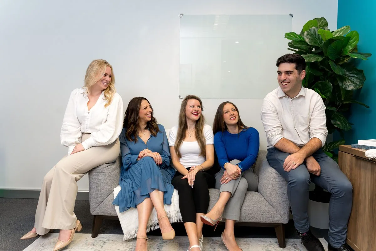 The Social Space team laughing together on the couch in the clinic