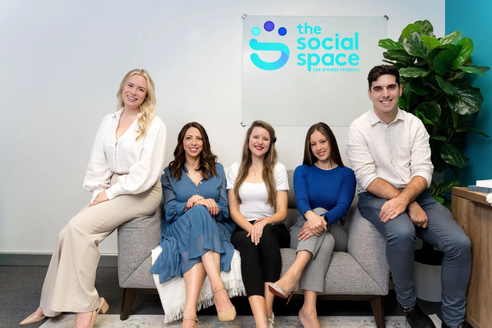 The Social Space team seated together beneath the clinic's sign
