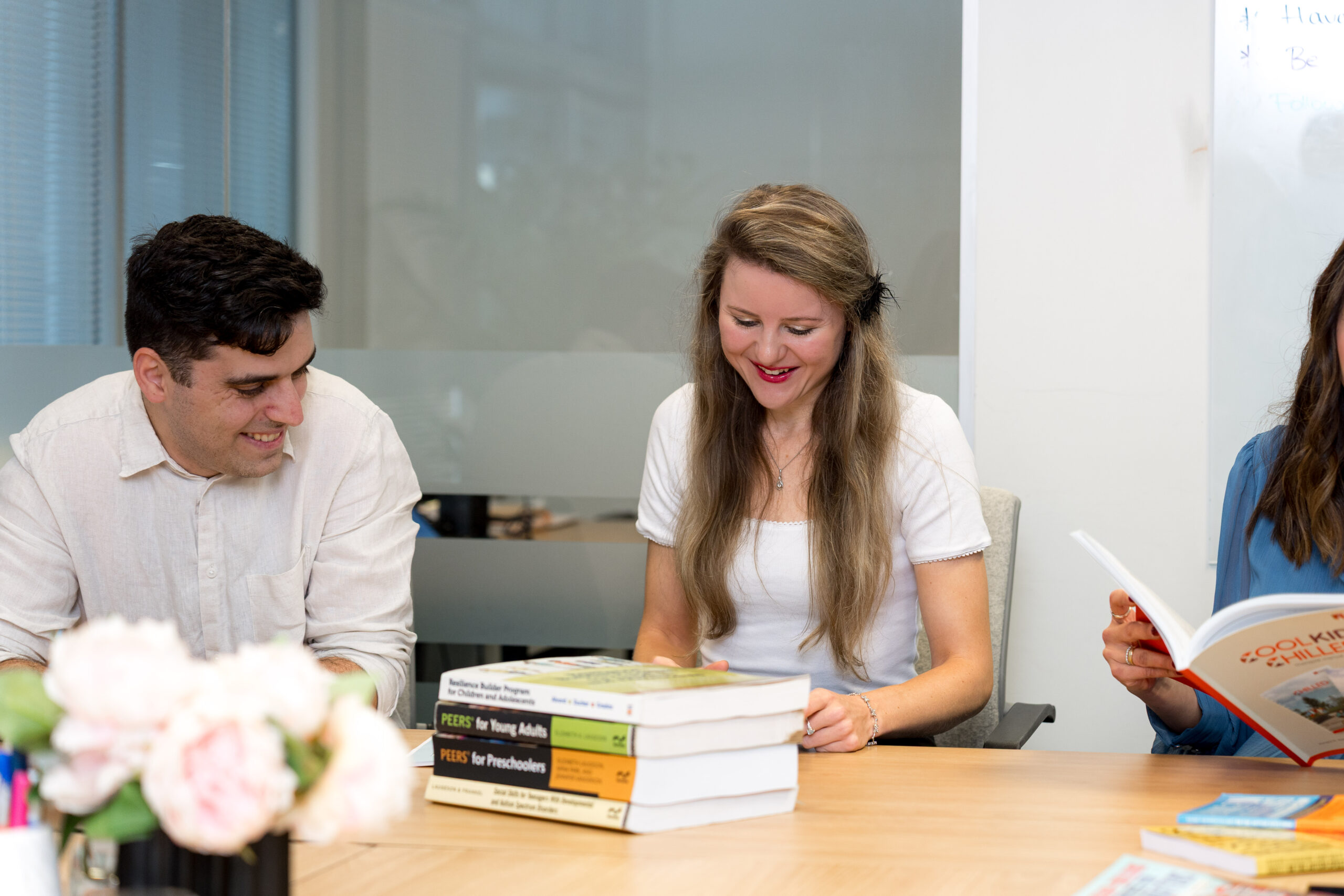 Team members at a table with a stack of PEERS® program manuals