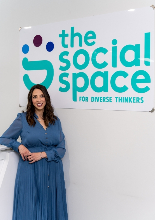 A psychologist standing beside The Social Space sign at the clinic